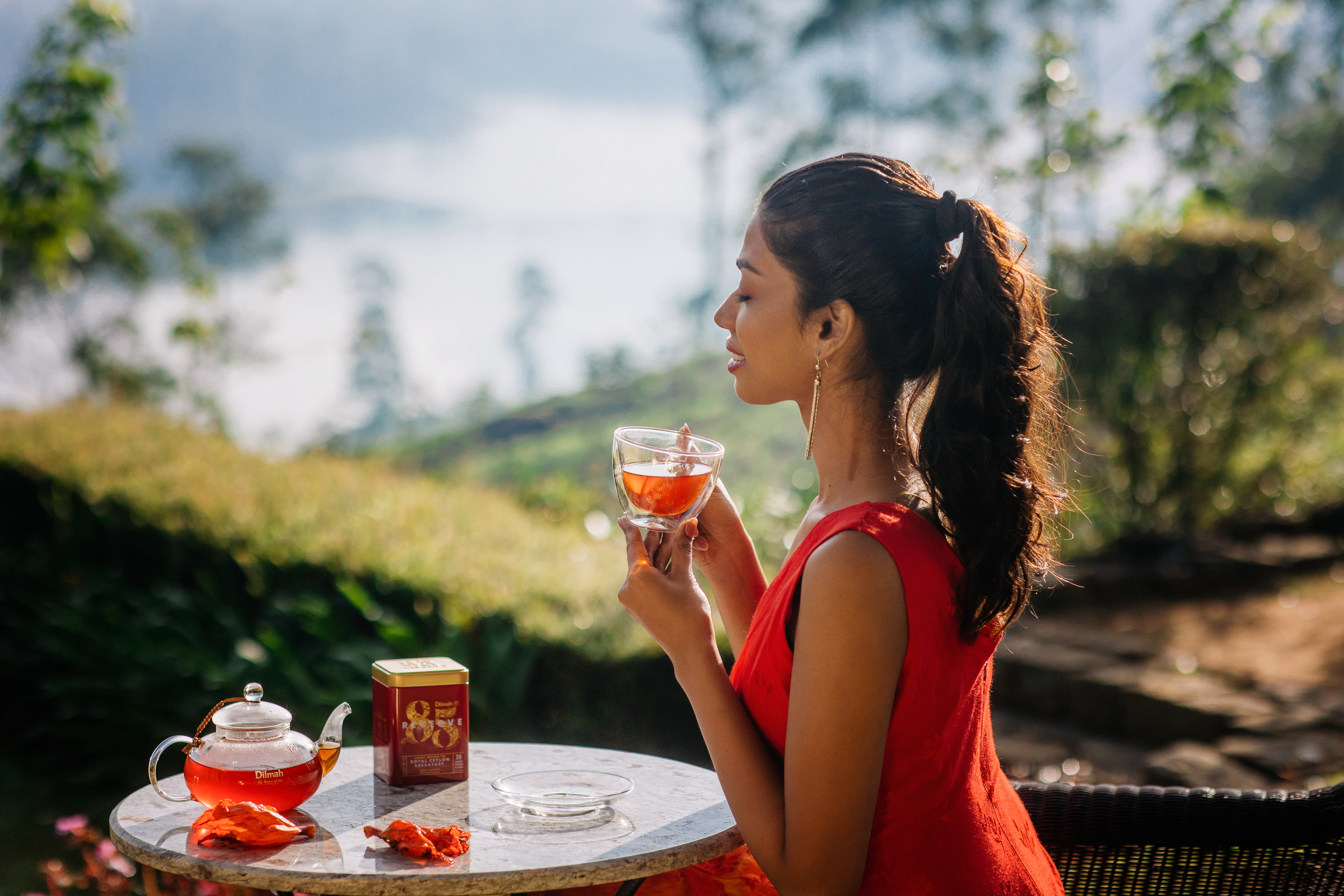 Kobieta delektująca się herbatą Dilmah Rose, Lychee & Vanilla na tarasie.