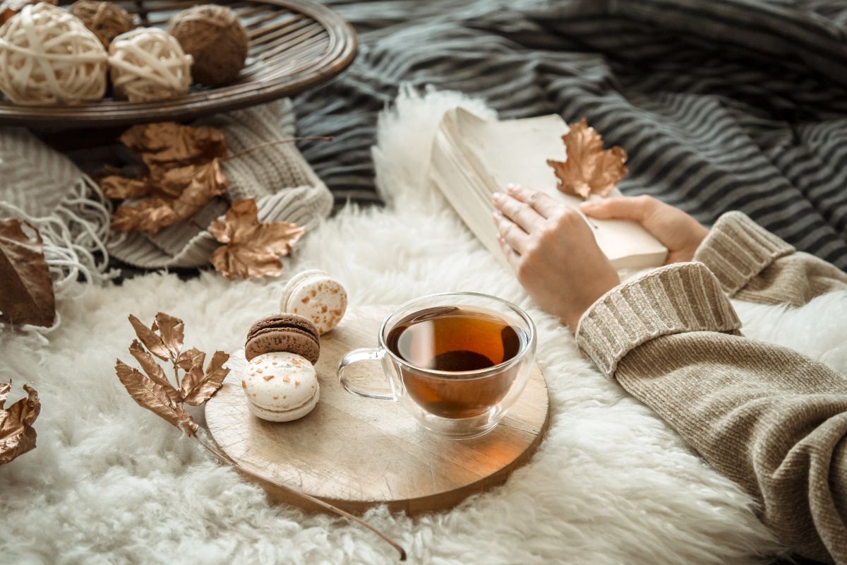 Napar z mięty z cynamonem w przezroczystej szklance. Obok bułeczki cynamonowe, laski cynamonu i opakowanie Dilmah Exceptional Peppermint Leaves with Ceylon Cinnamon.